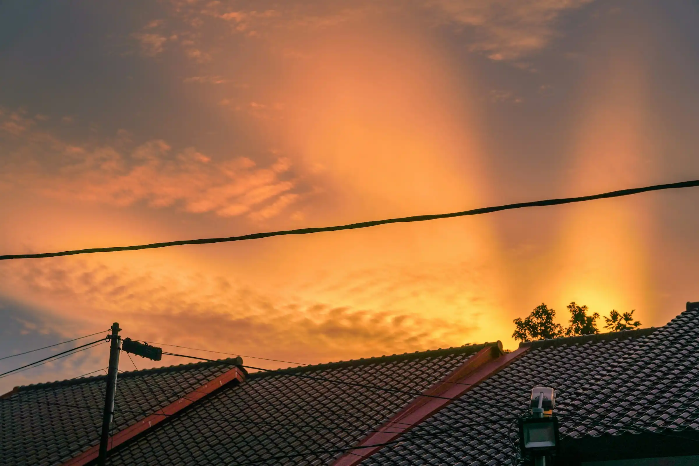 The sun setting behind a row of rooftops.